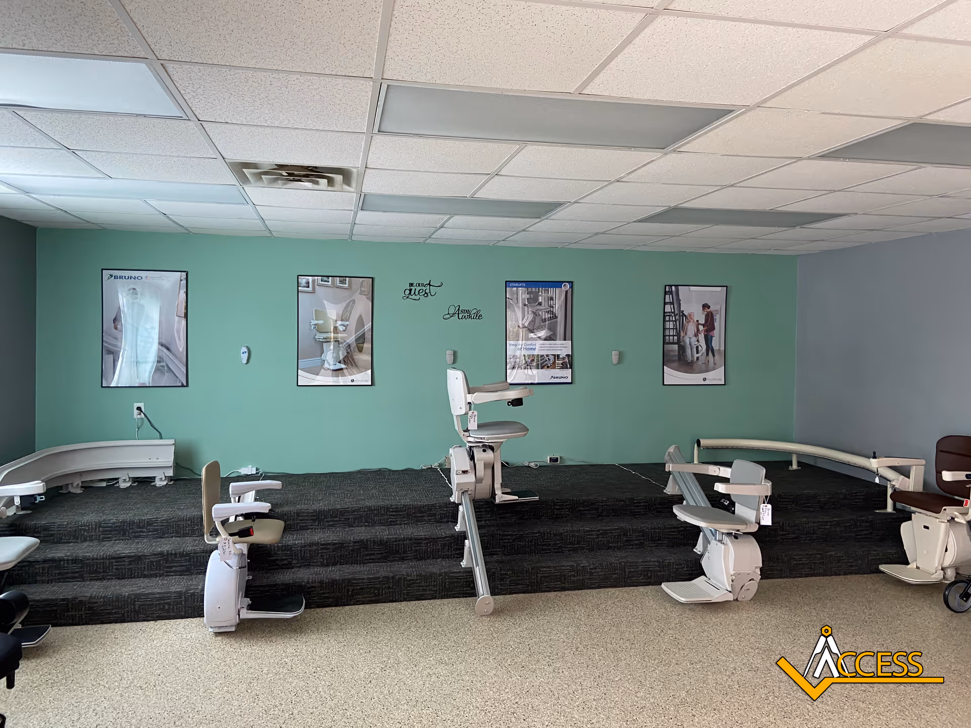 Interior showroom with patient transfer chairs on a raised platform against mint-green wall.