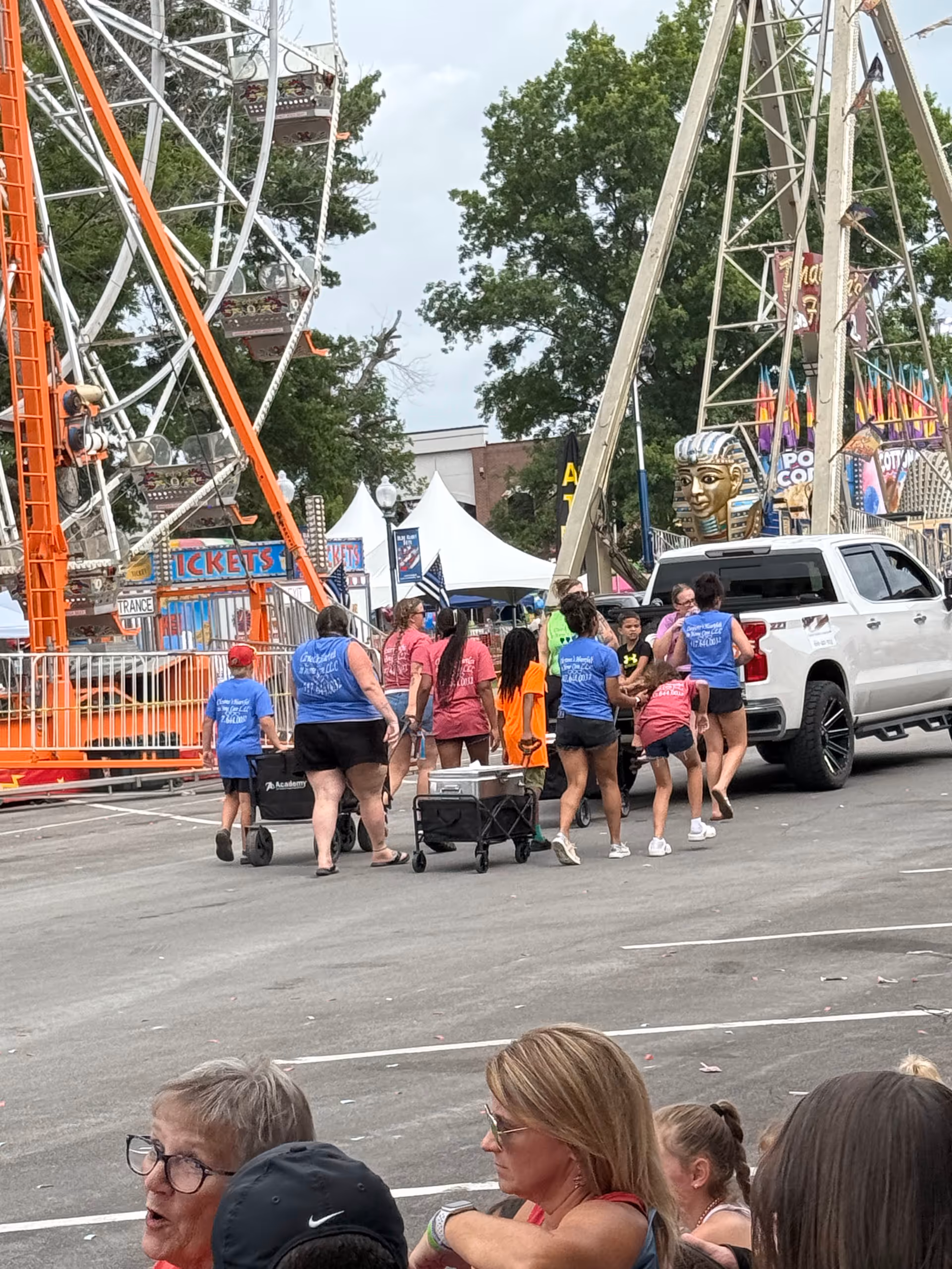 Group of people outdoors near a carnival ride and tents at a fair.