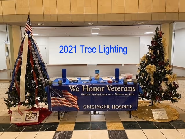 Lobby display table with banners and two decorated Christmas trees for 2021 Tree Lighting.