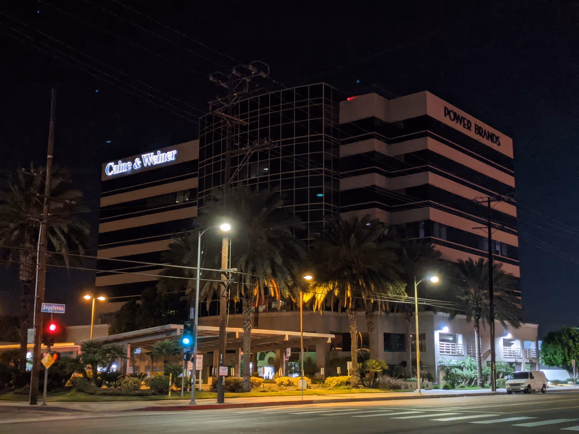 Night exterior of a multi-story building with palm trees and illuminated signage