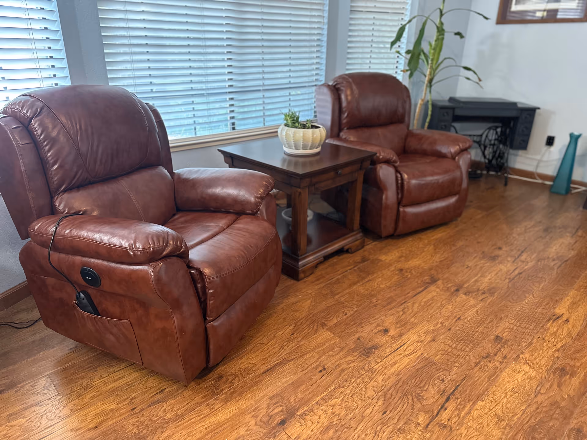 Two brown leather recliners with a wooden side table in a cozy living room.