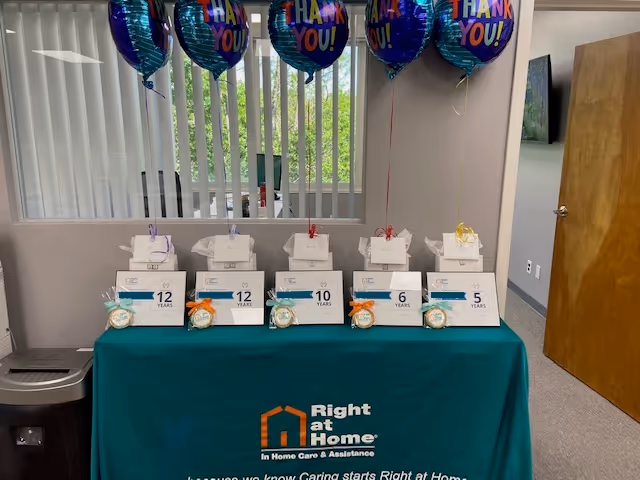 Indoor celebration setup at Right at Home with gift boxes, balloons, and a branded table.