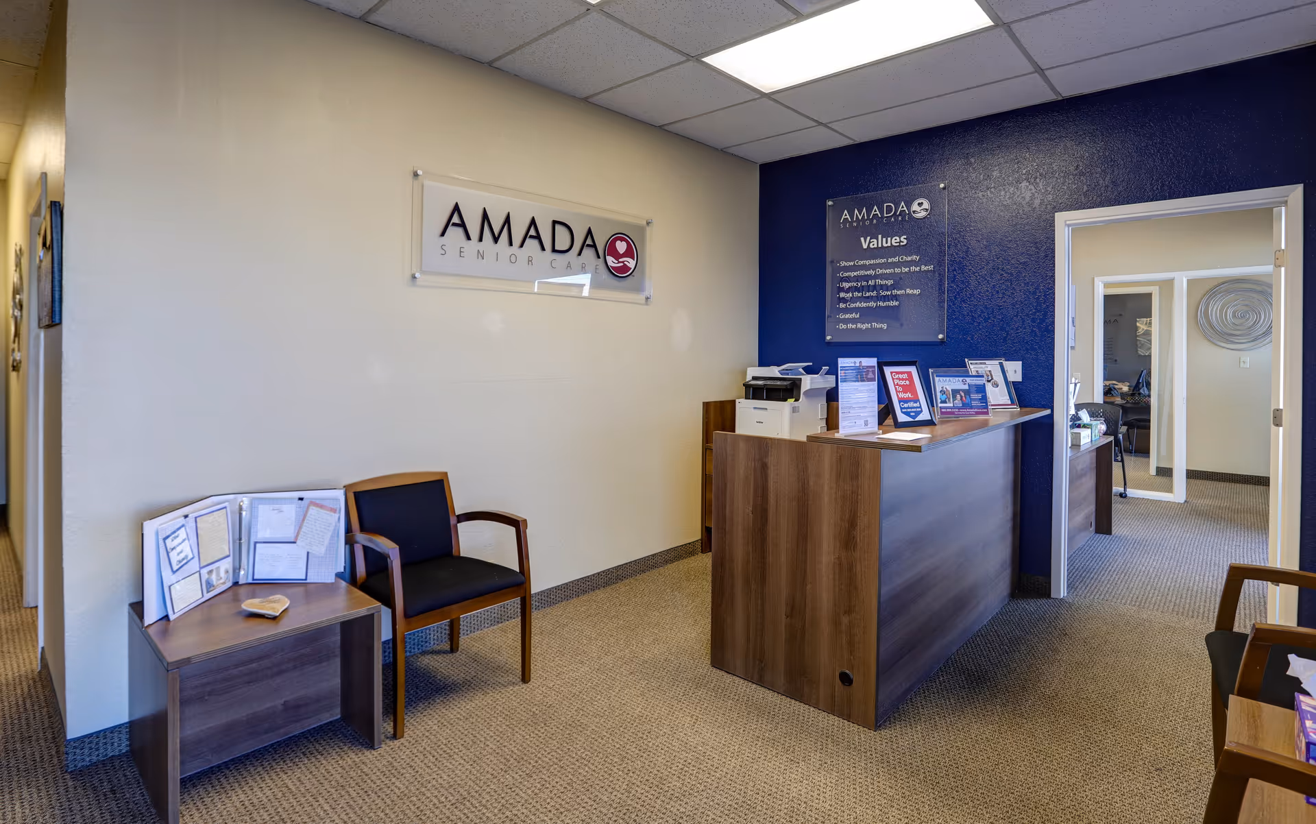 Reception area of Amada Senior Care with a front desk, seating, and information displays.