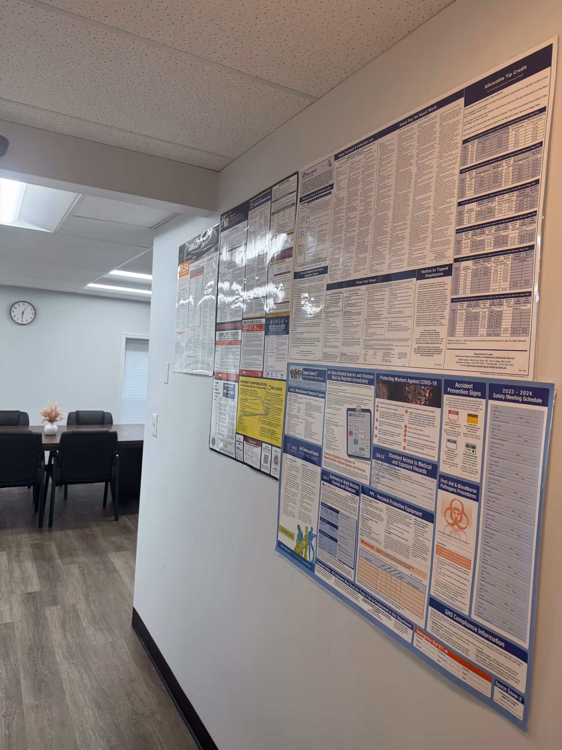 Interior hallway featuring large wall mounted informational boards and a conference table.