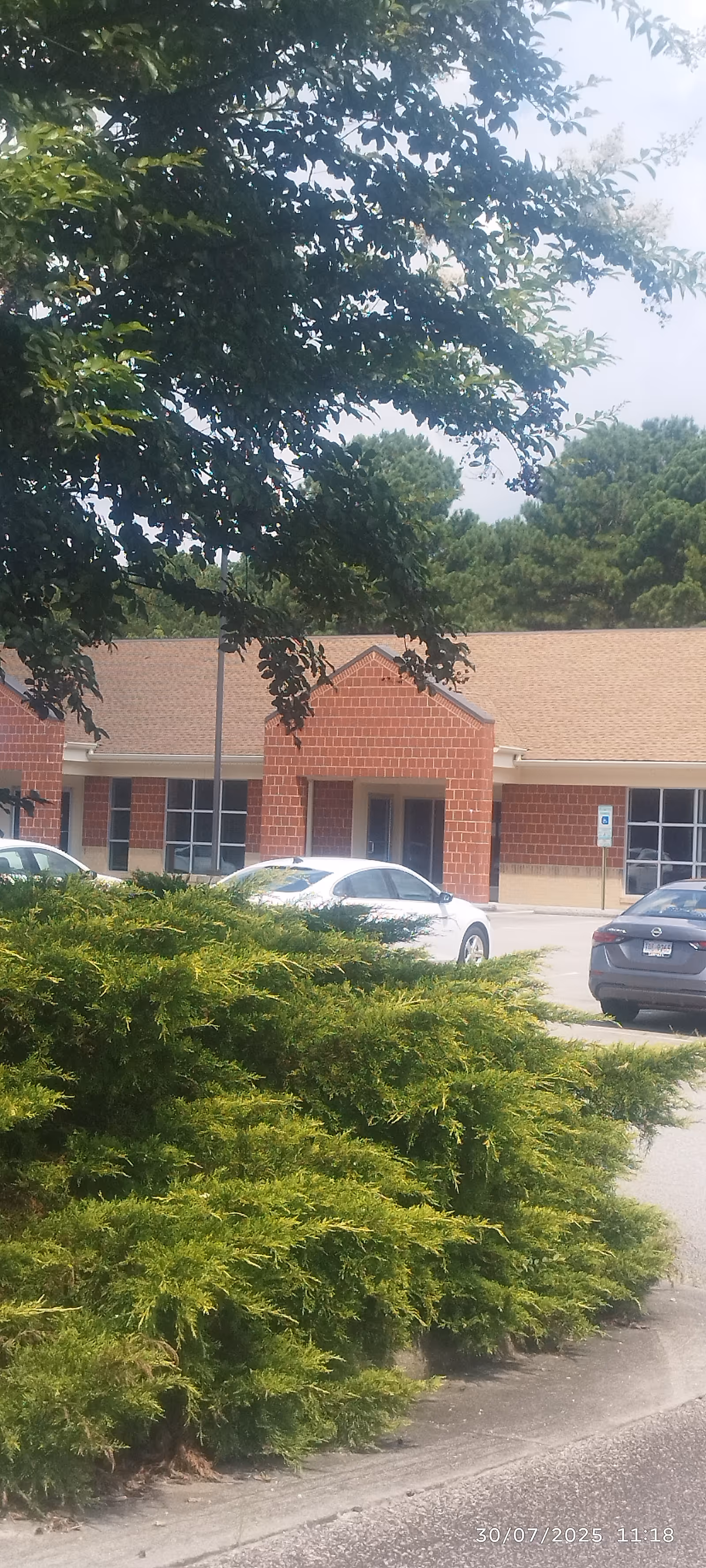 Exterior view of a brick senior living facility with a parking lot and greenery
