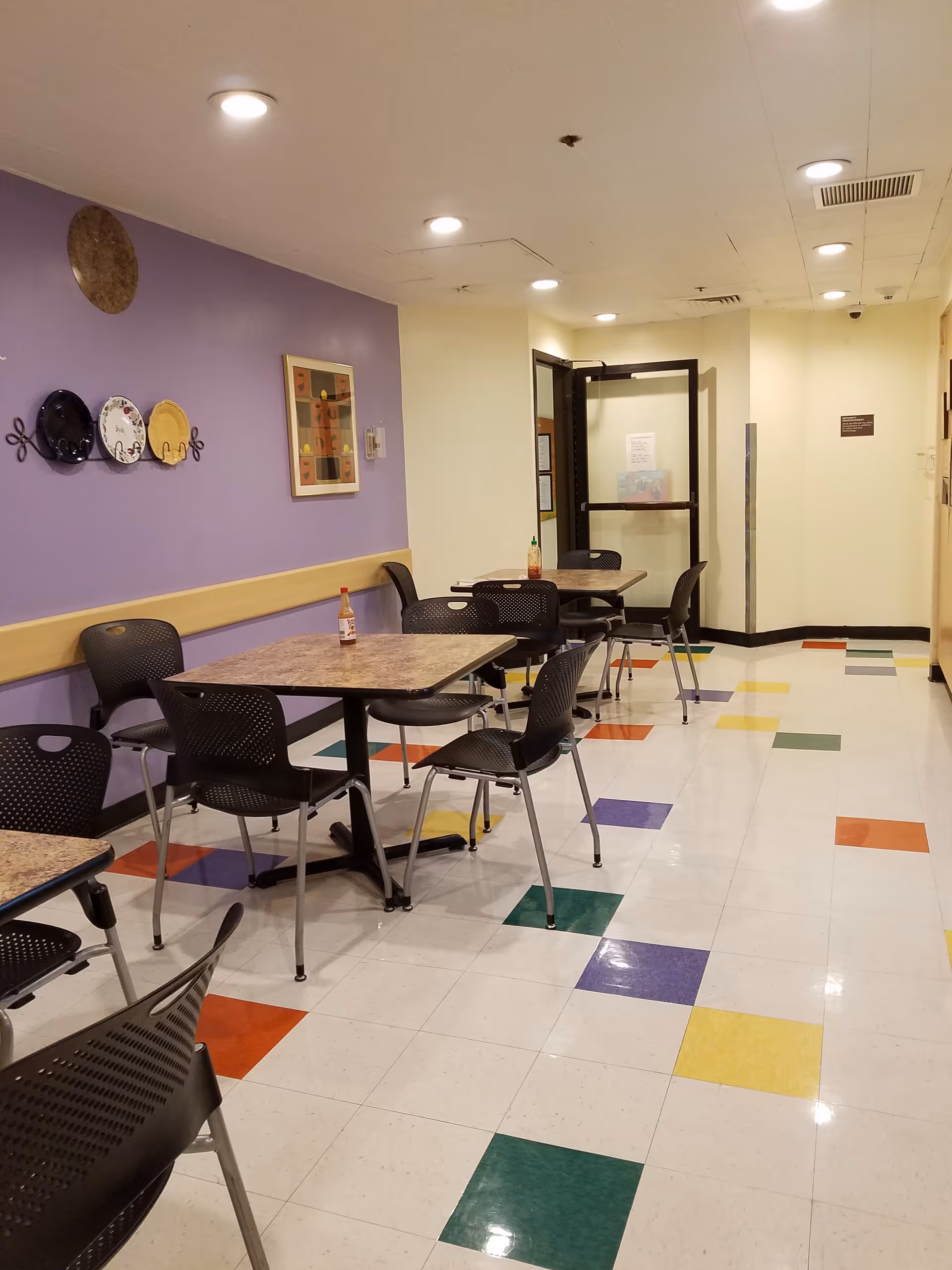 Interior dining area at Redlands Community Hospital with tables, chairs, and a colorful tiled floor.