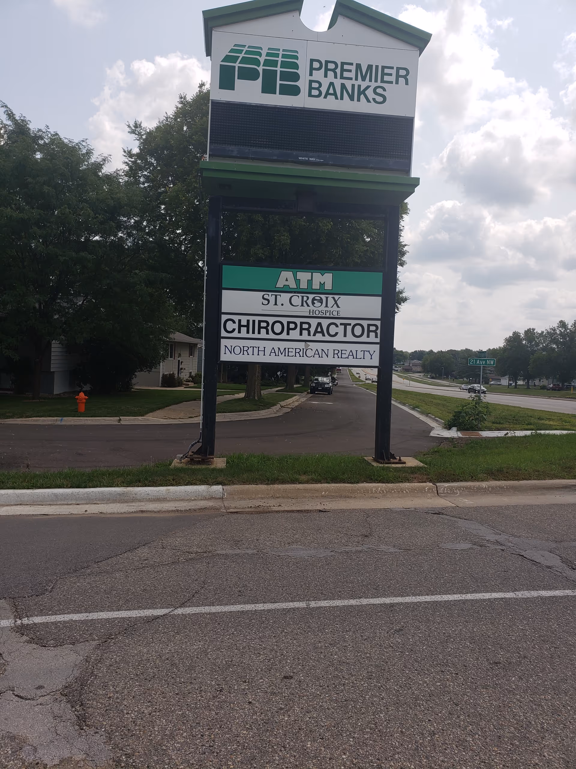 Tall outdoor signboard displaying Premier Banks, ATM, St. Croix Hospice, chiropractor, and realty.