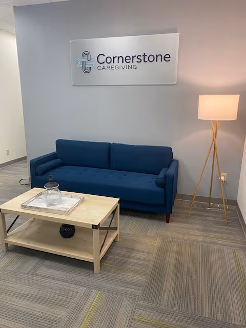 Blue couch and coffee table in a modern waiting area with Cornerstone Caregiving sign