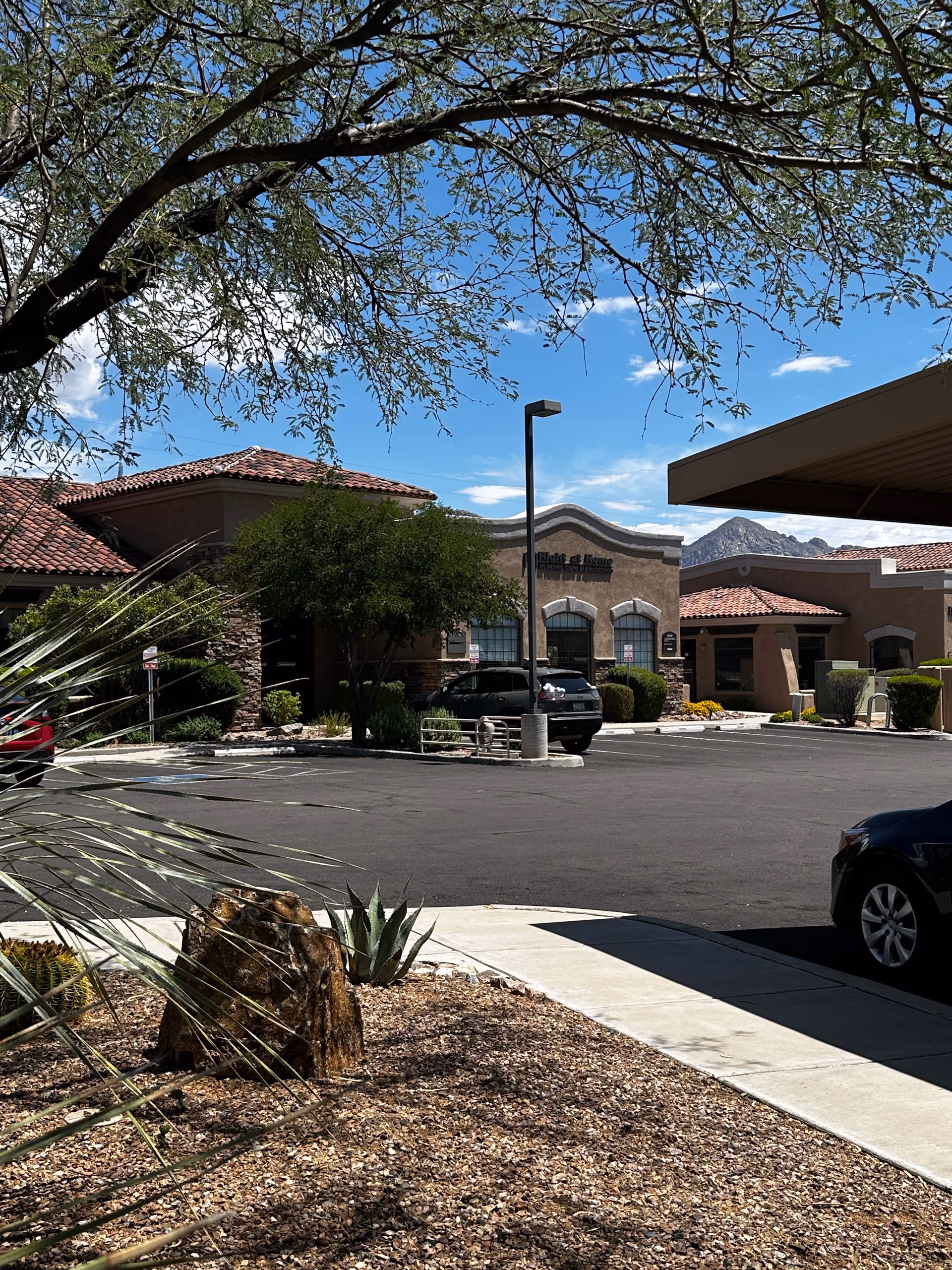 Exterior view of Right at Home senior living facility with parked cars and desert landscaping.
