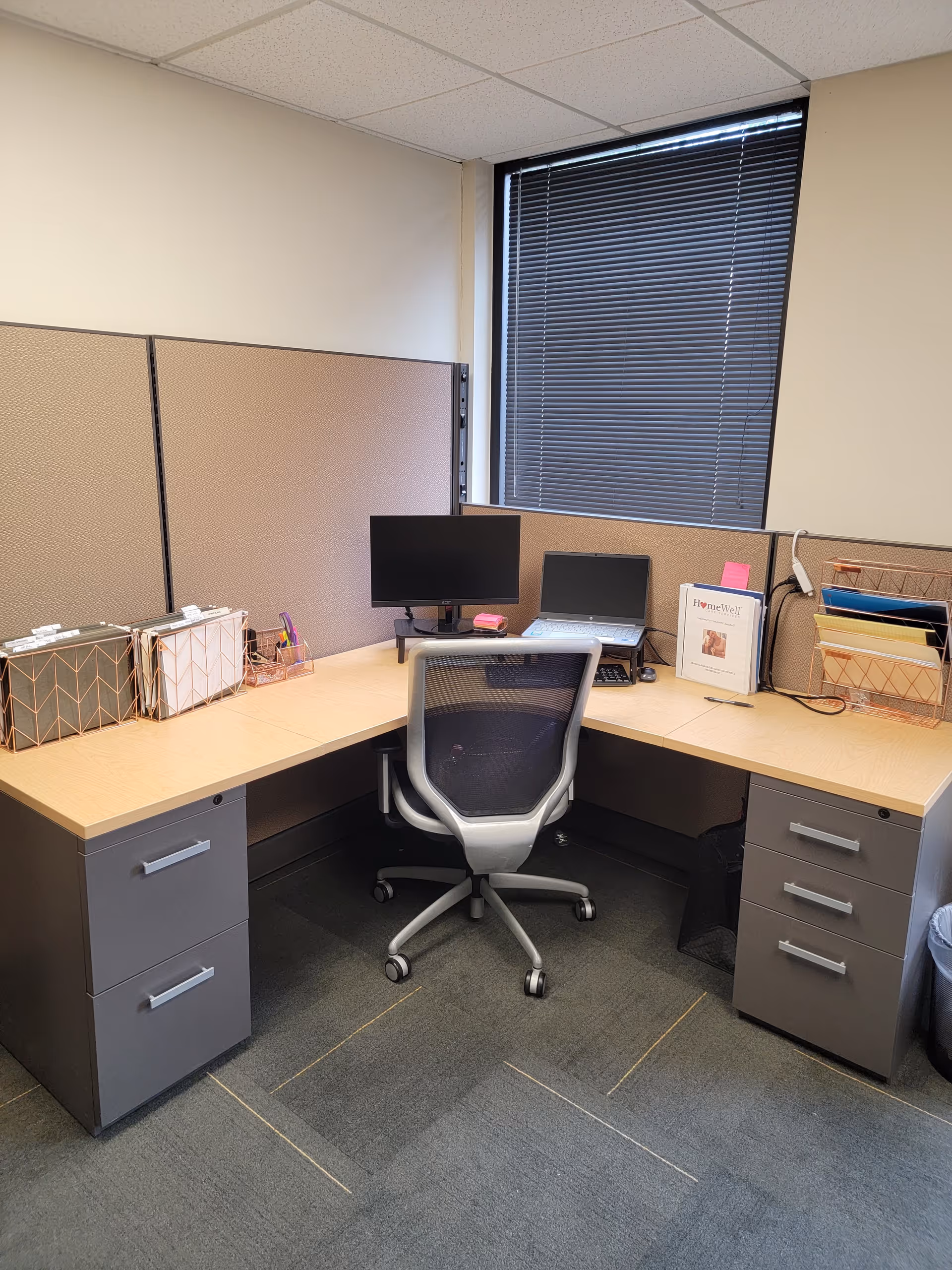 Office cubicle in a senior living facility with desk, computer, and chair.