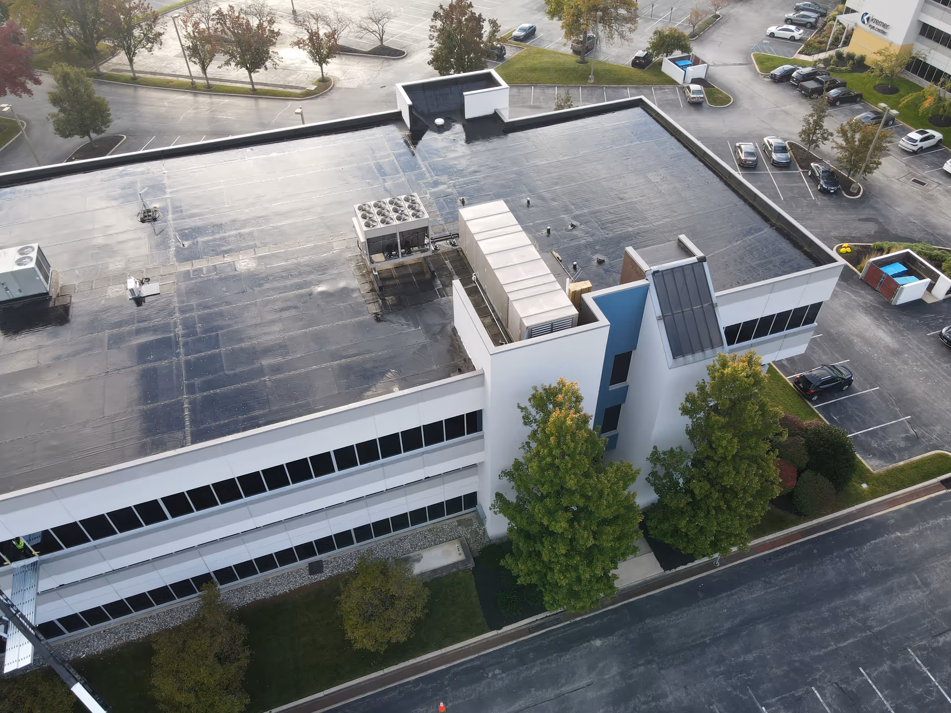 Aerial view of a modern medical facility with flat rooftop and parking.