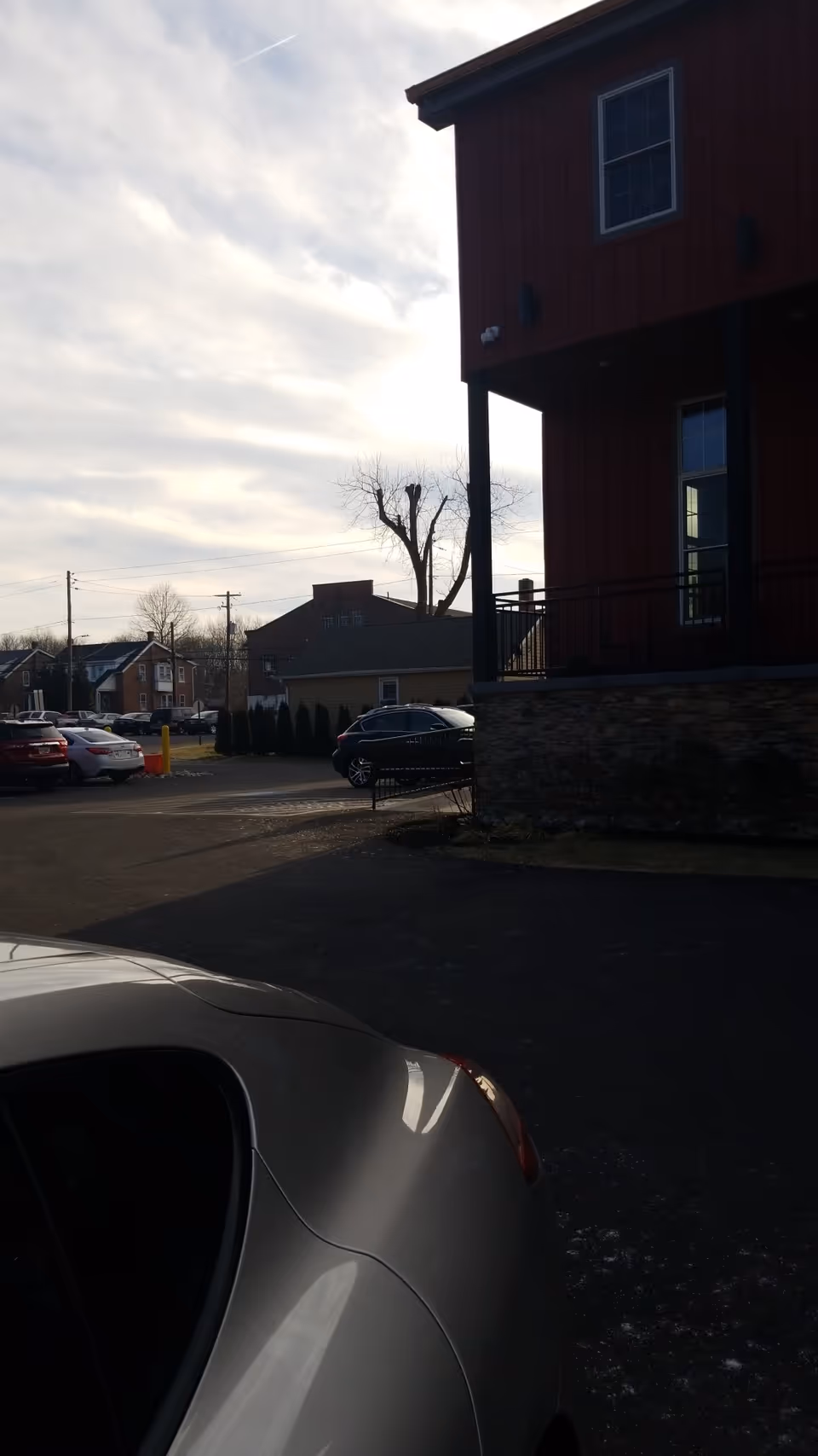 Exterior view of a red building with a stone base and parked cars.