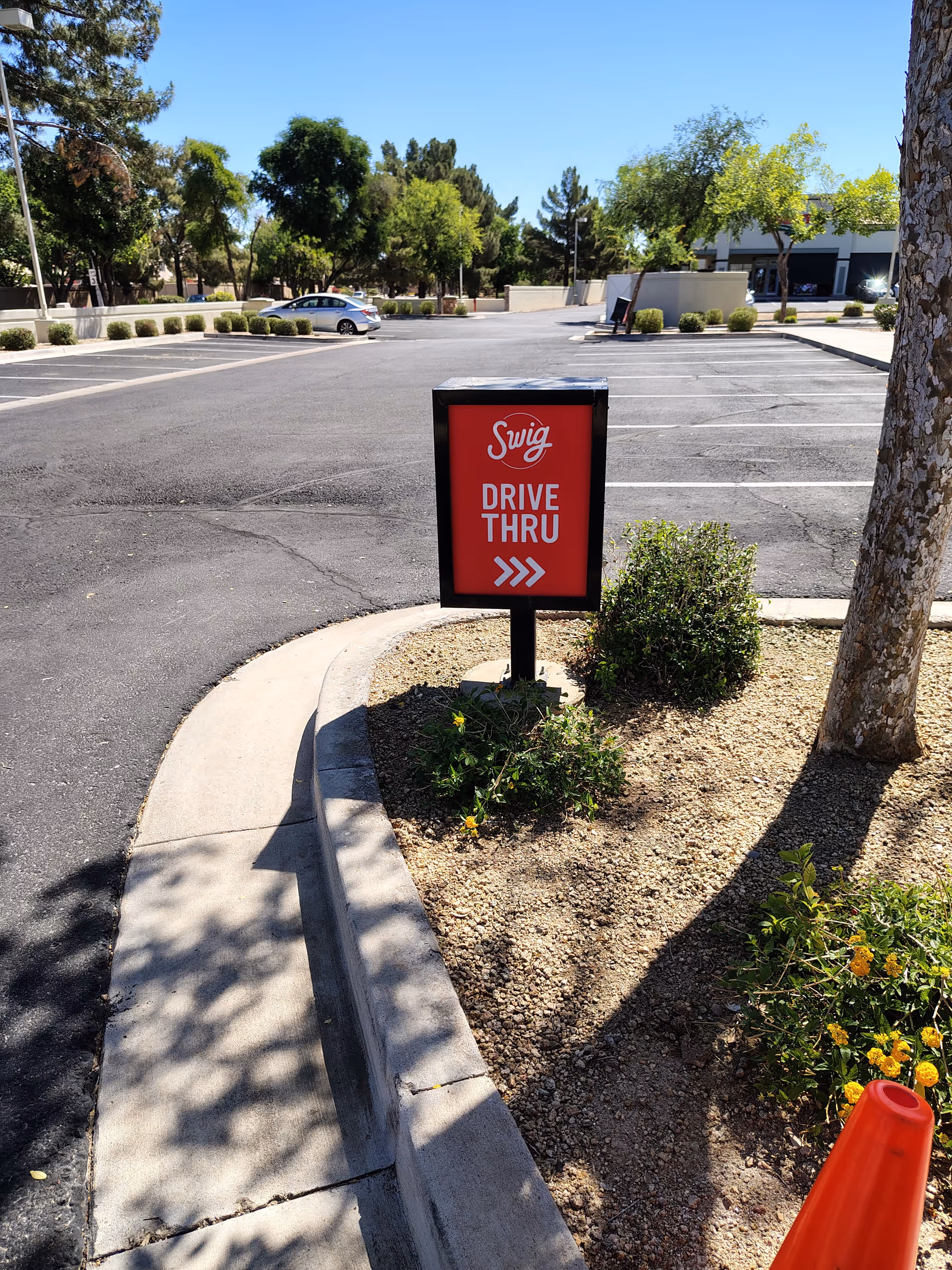 Red drive-thru sign in a parking lot by a facility entrance.