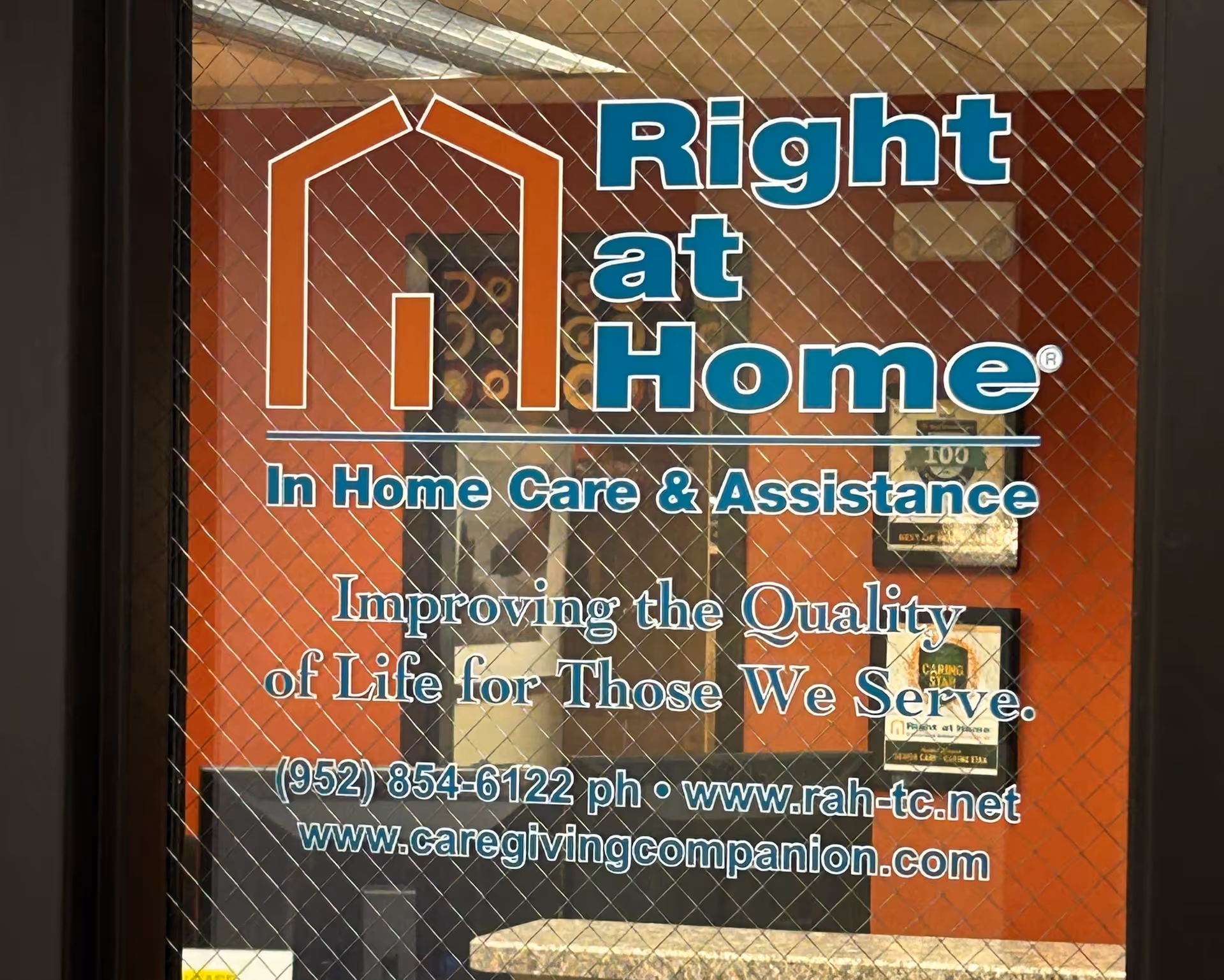 Glass door with Right at Home logo and contact info on orange background.