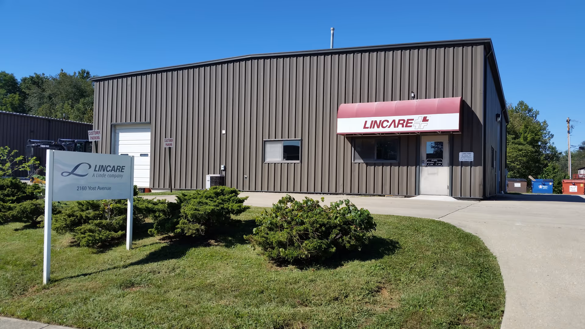Exterior view of a brown metal building with a red-and-white Lincare sign and a grassy foreground.