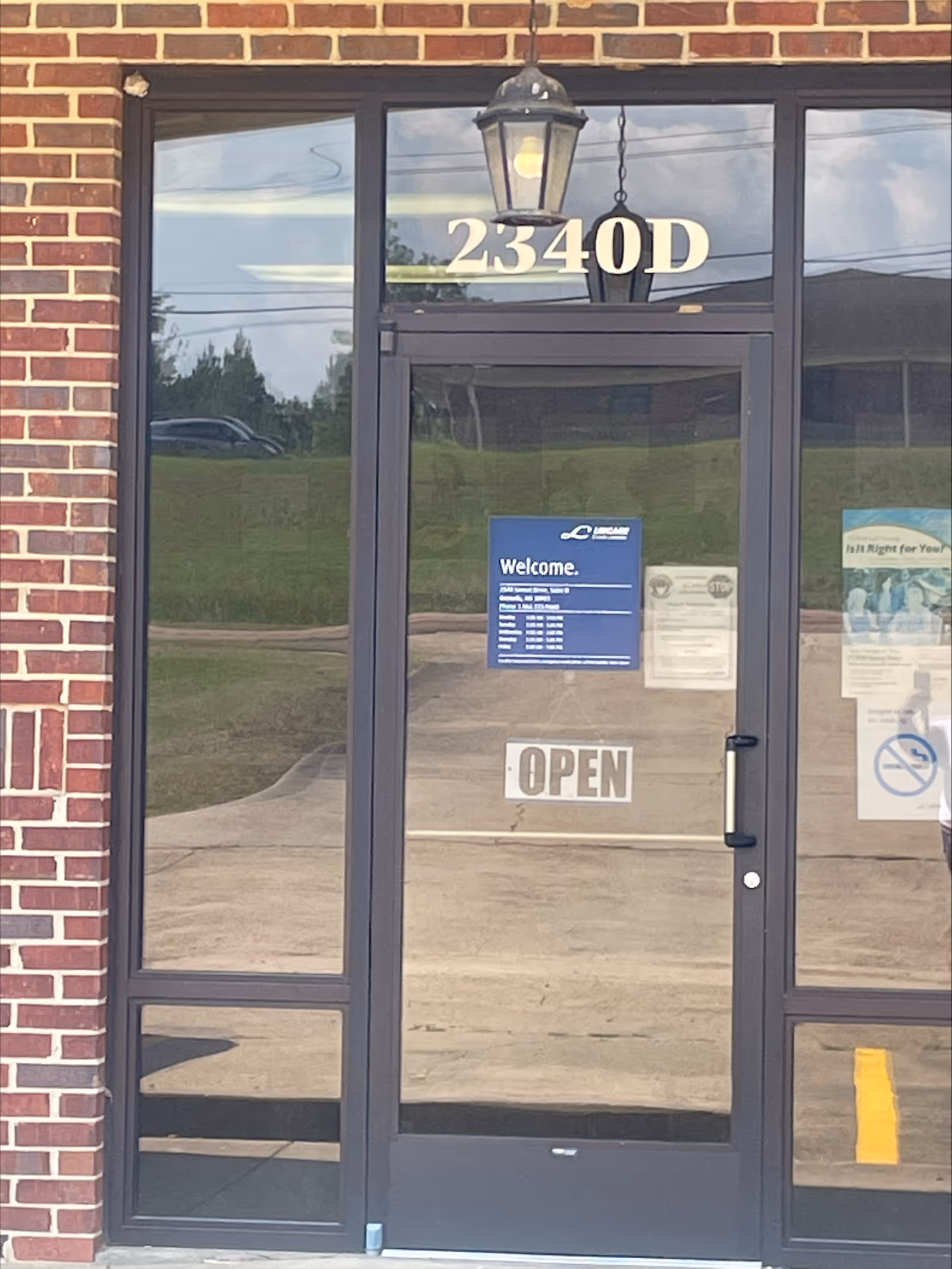 Front entrance of a brick building with glass doors and an OPEN sign.