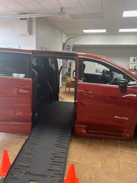 Red handicap-accessible van with an extended ramp displayed inside a showroom.