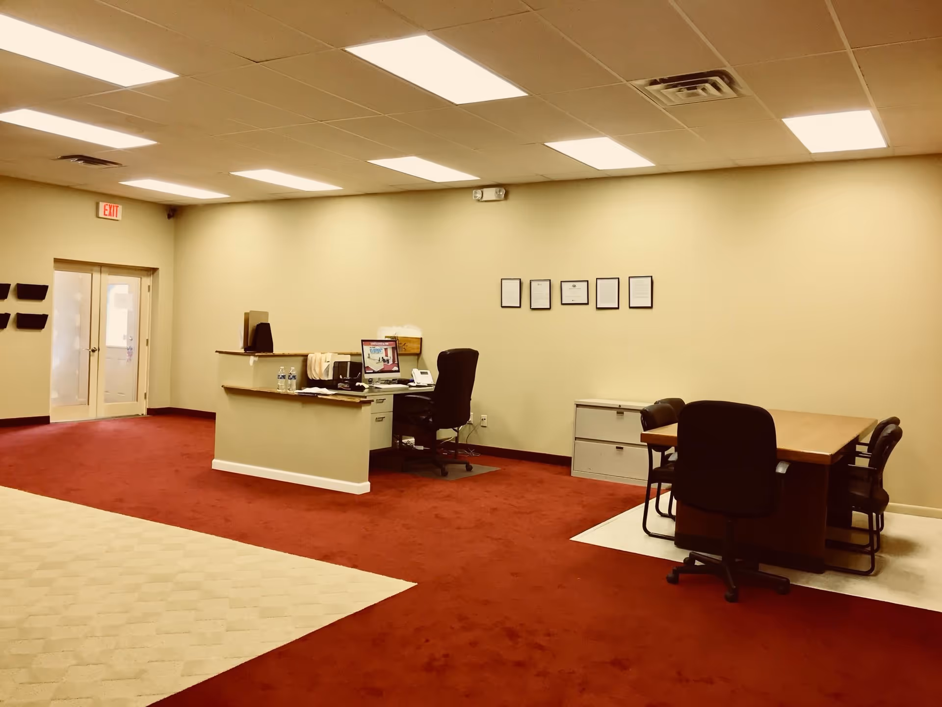 Lobby reception area with a desk, computer, chairs, and a conference table.