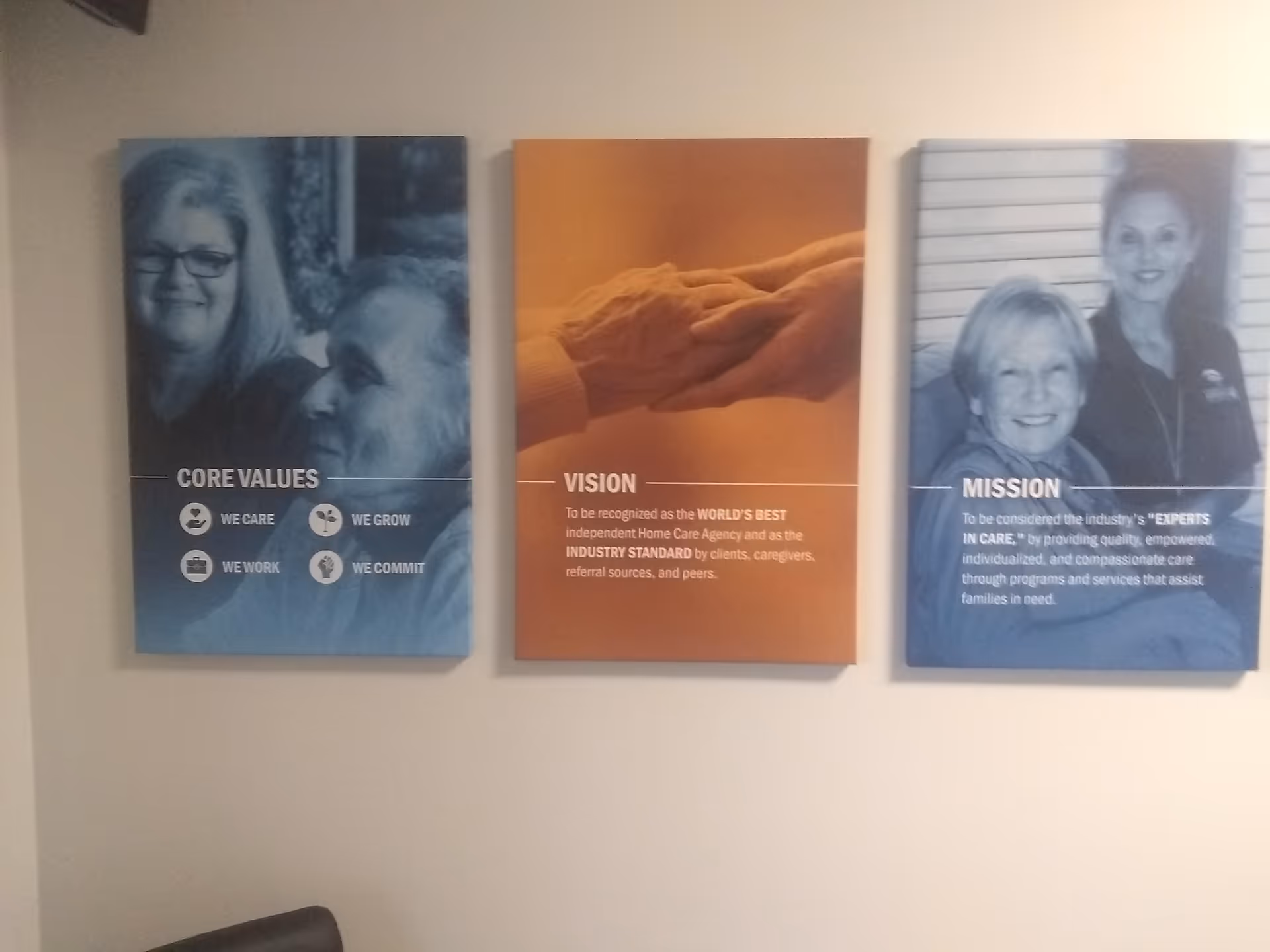 Three wall posters displaying core values, vision, and mission in a hallway.