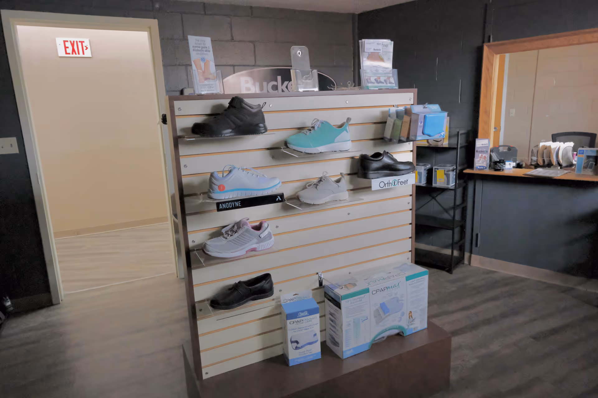 Shoe display rack with athletic shoes and medical supplies inside a clinic-like interior.
