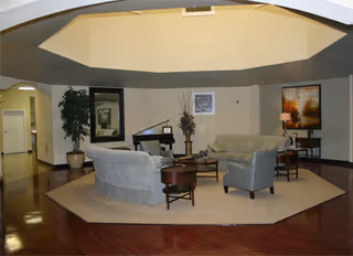 Interior of Harbor Hospice of Beaumont lounge with couches, tables, plants, and art.