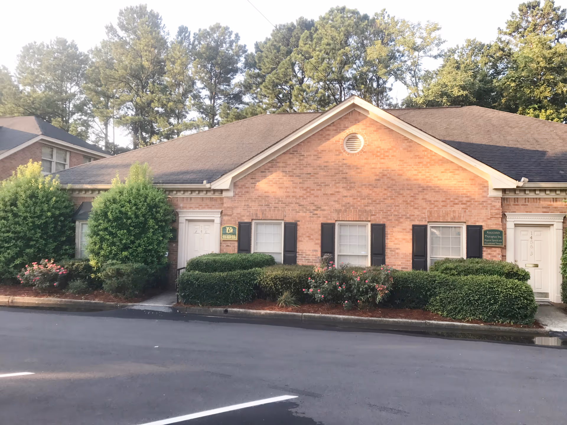 Front exterior of a brick senior care building with trimmed hedges.