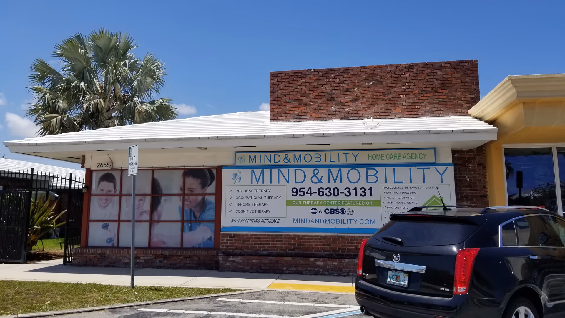 Exterior view of Mind & Mobility building with large sign and parked car.