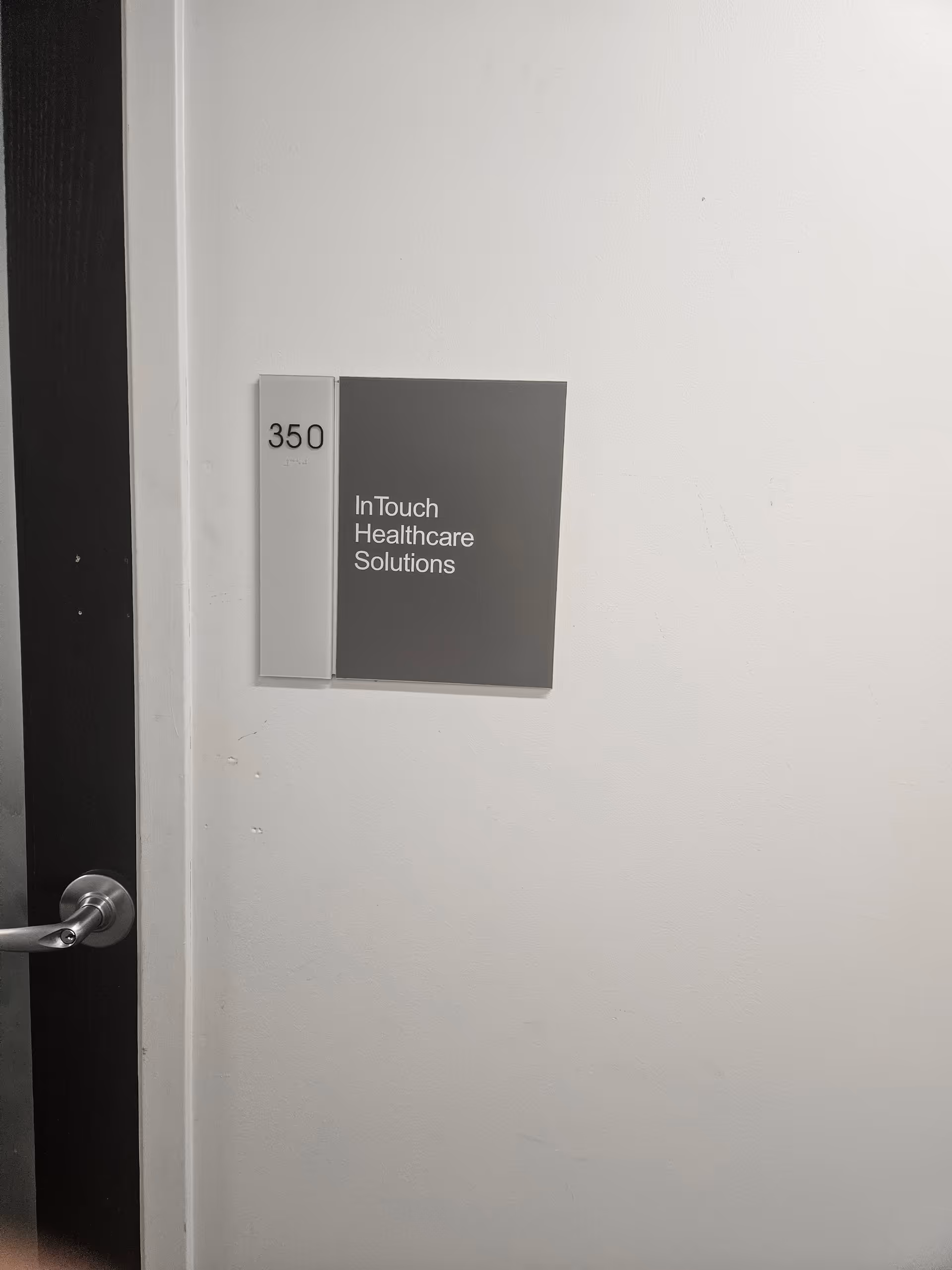 White hallway wall with a gray sign reading InTouch Healthcare Solutions and room 350.