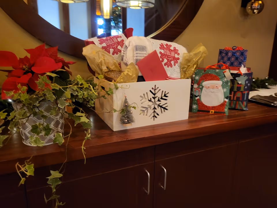 Holiday gift bags, poinsettia, and ivy decor on a wooden counter