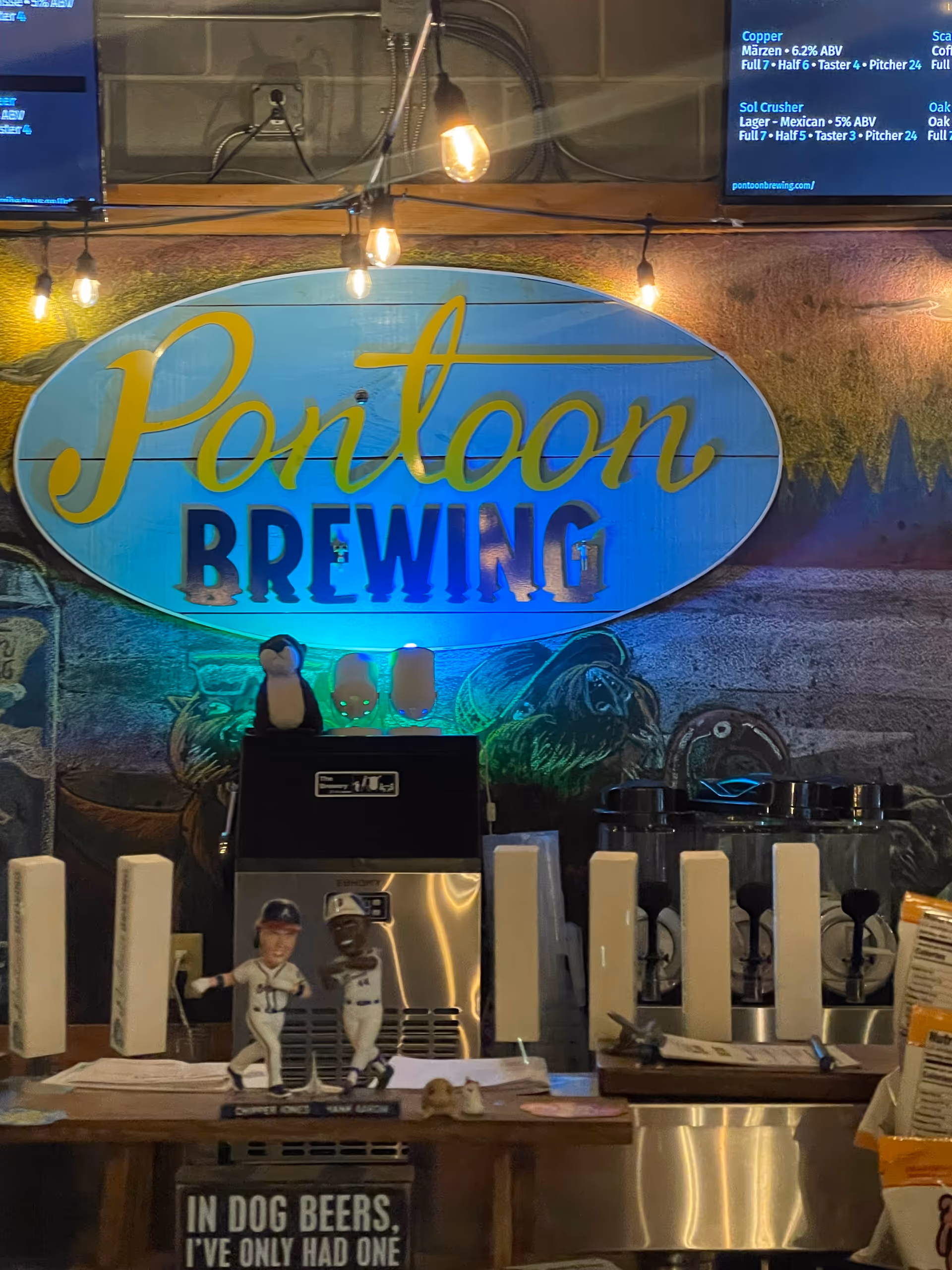 Indoor brewery bar area with Pontoon Brewing sign and beer taps under warm hanging lights.