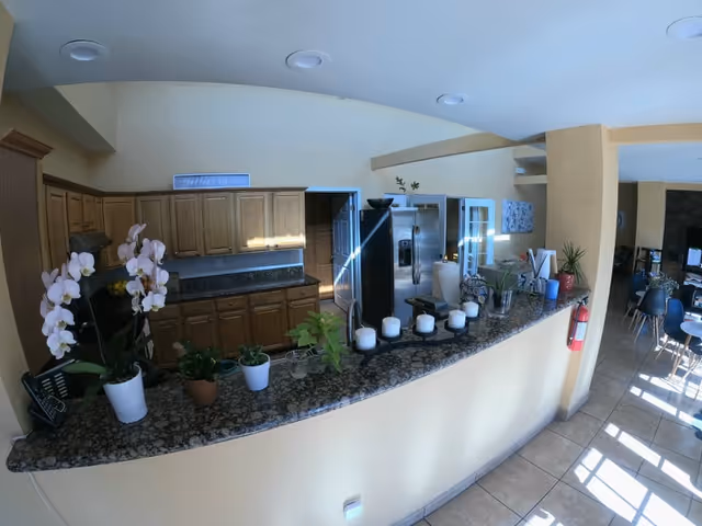 Long granite counter with candles and plants, kitchen cabinets and appliances in a senior living area.