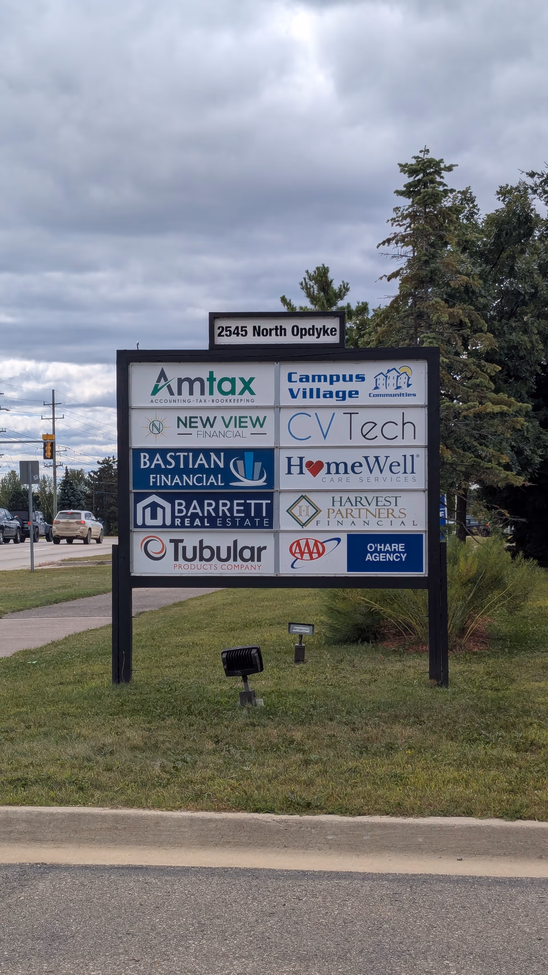 Outdoor sign displaying multiple company logos, including HomeWell Care Services, at a street-facing lot.