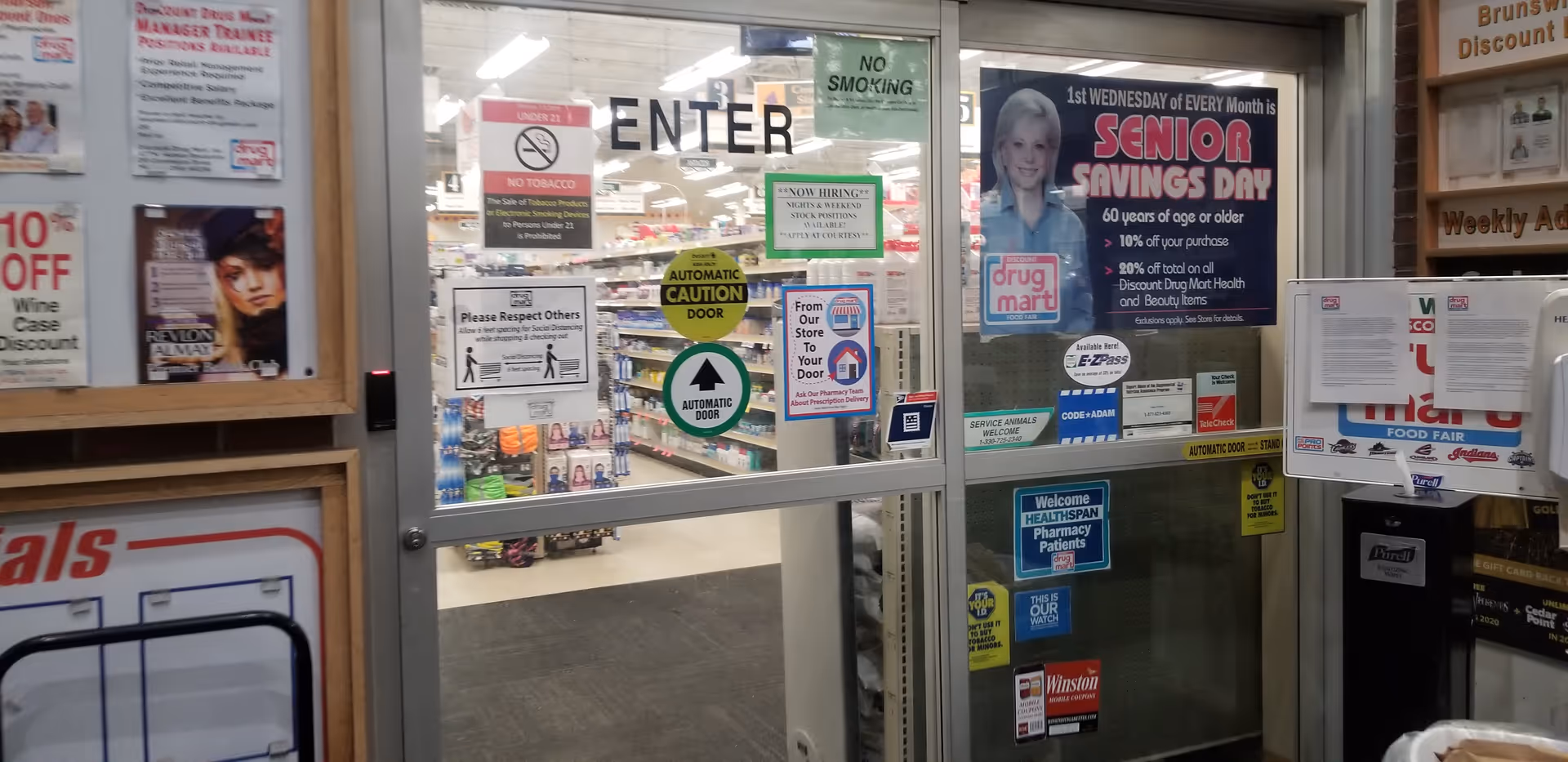 Glass doors marked ENTER lead into a busy Discount Drug Mart interior with posters.