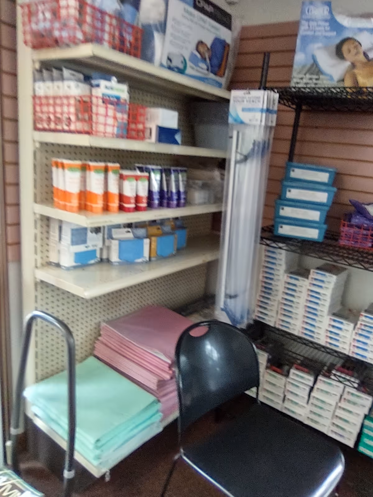 Supply closet in a senior facility with shelves of medical supplies and a chair.