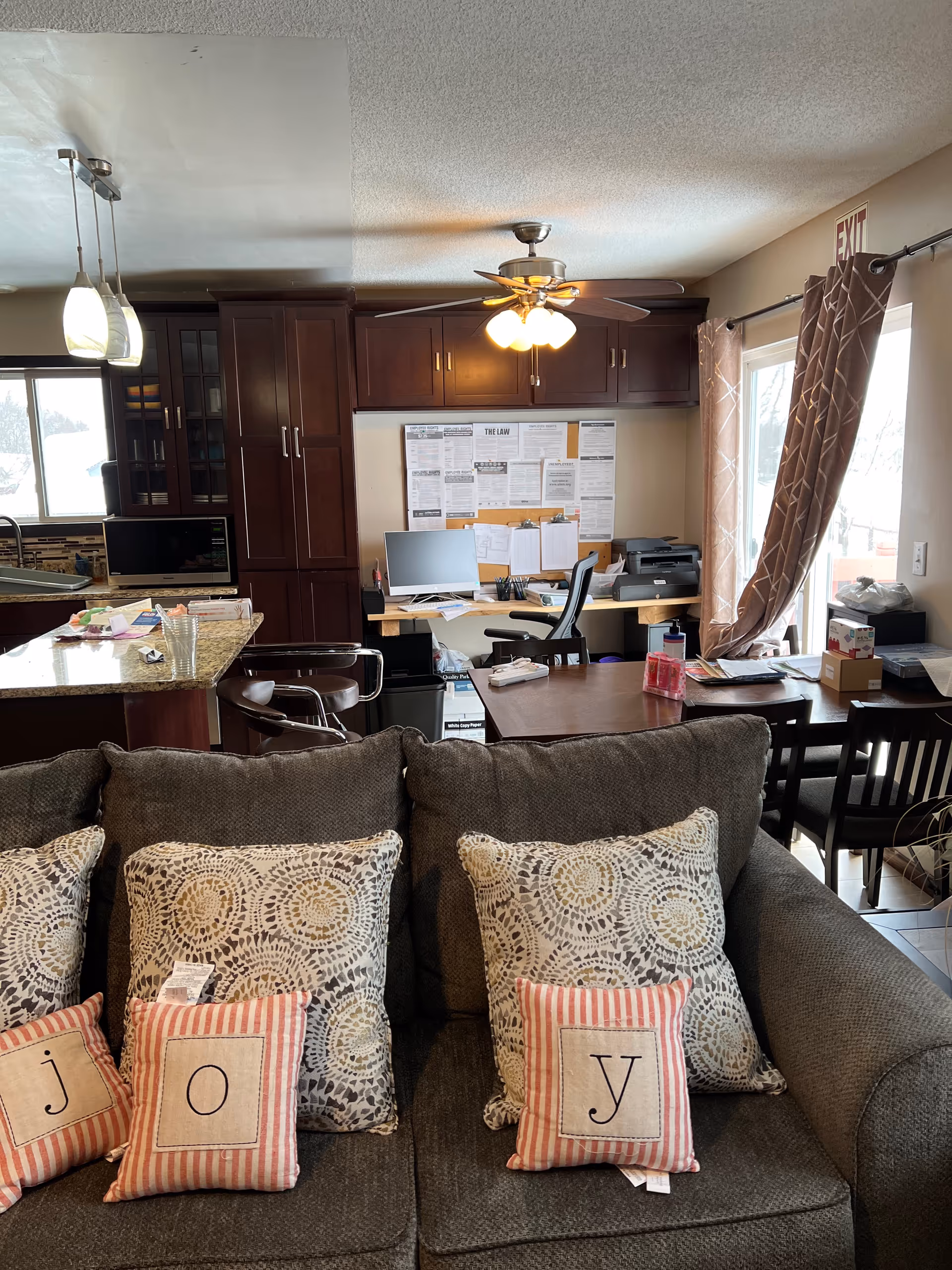 Interior living room area with a grey sofa, patterned cushions, and a desk.