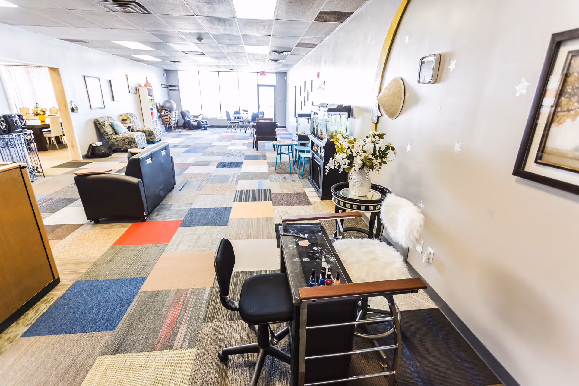 Bright common area with seating, chairs, and a manicure/nail station along the wall.