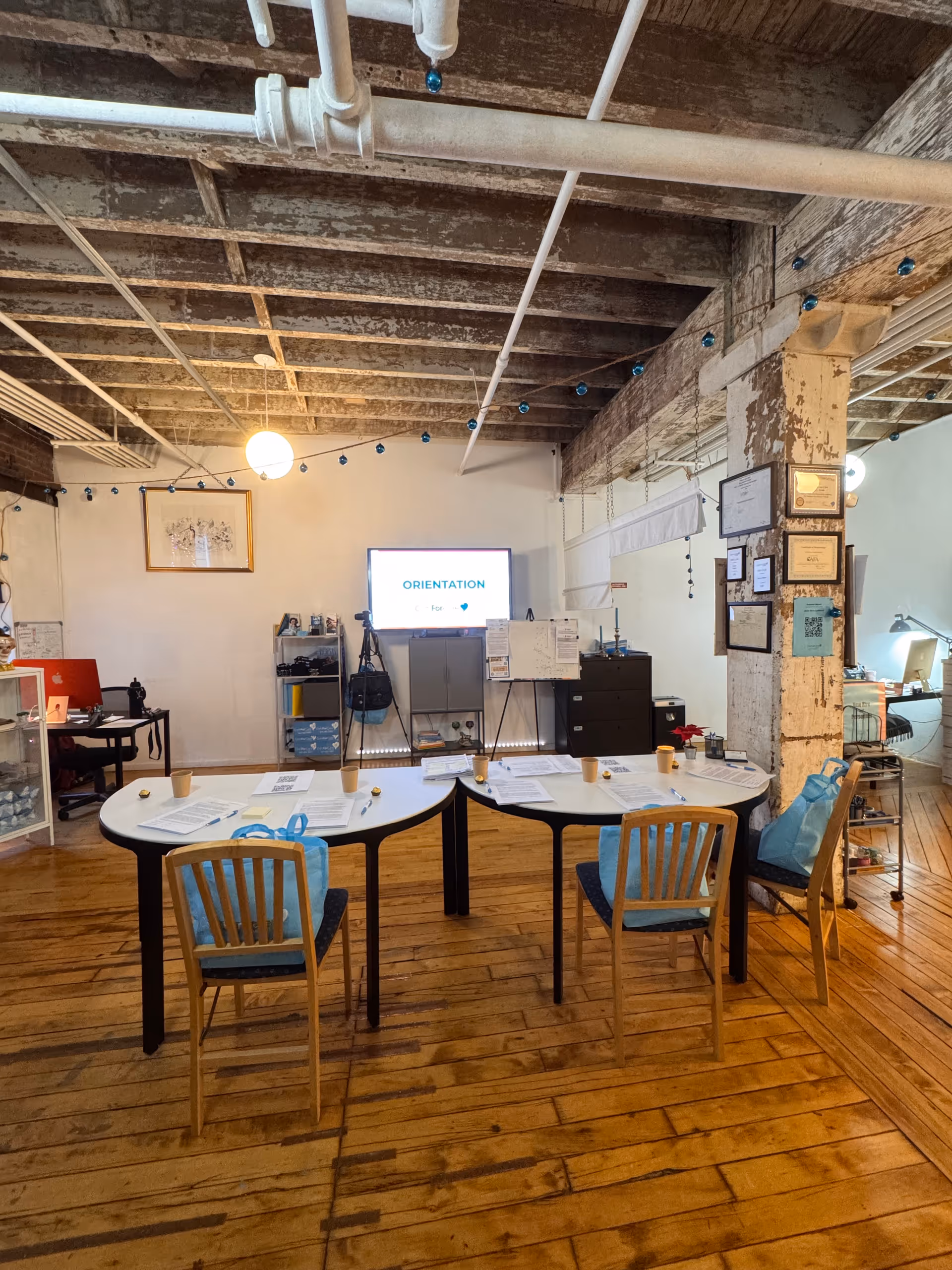 Industrial-style interior with exposed beams, a curved table, papers, and an orientation screen.