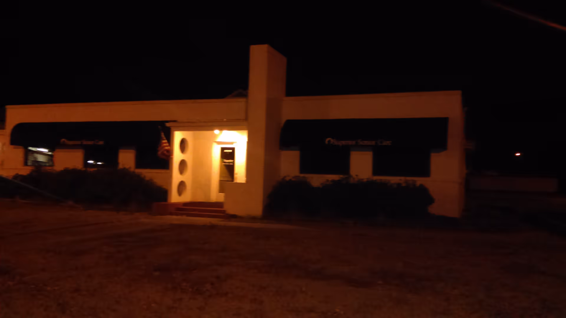 Night exterior of Superior Senior Care facility with lit doorway and dark awnings.