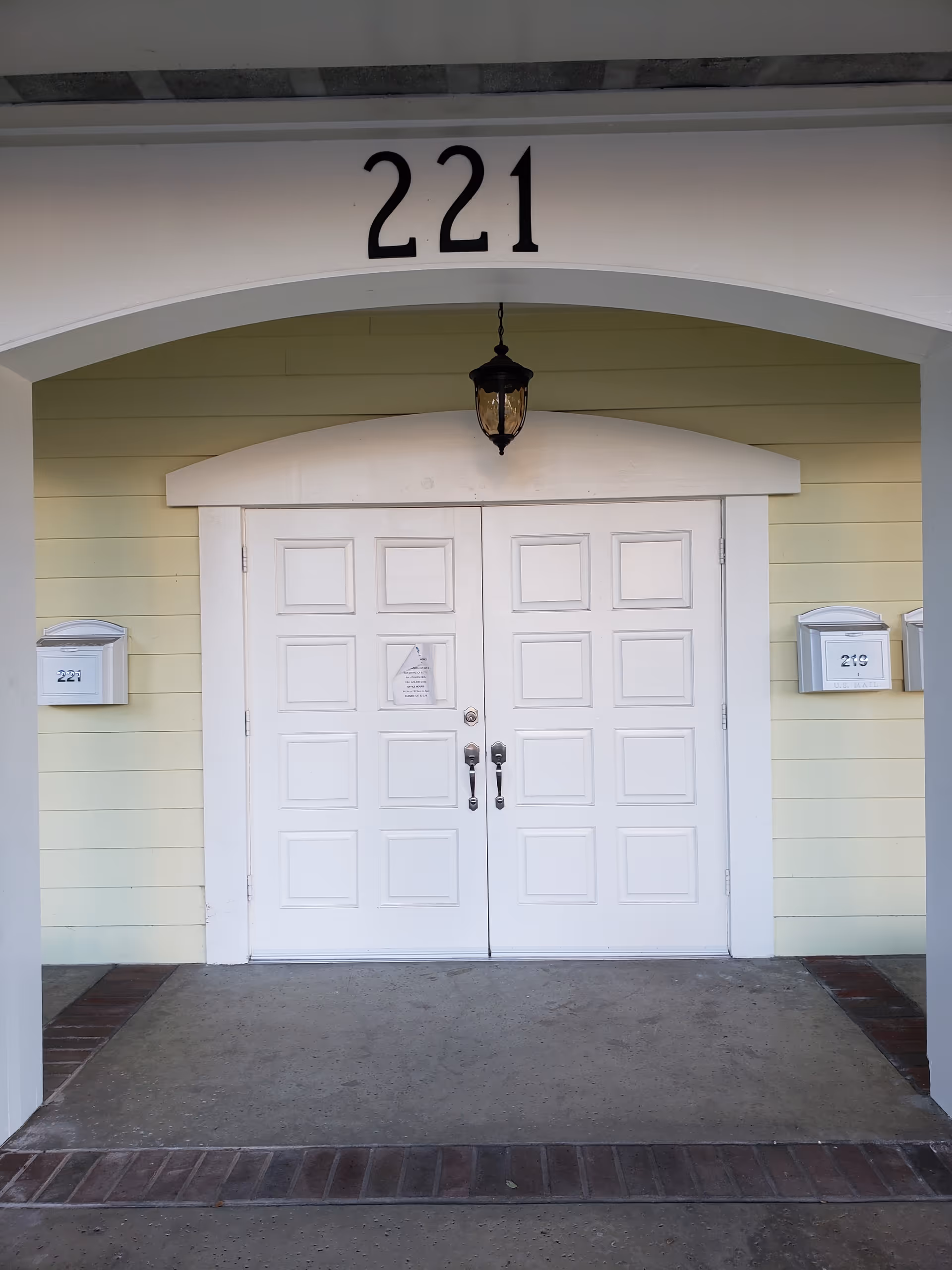 White double doors beneath an arched entry with the number 221 above.