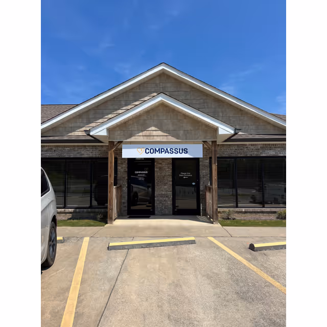 Front view of Compassus facility entrance with glass doors and a peaked awning.