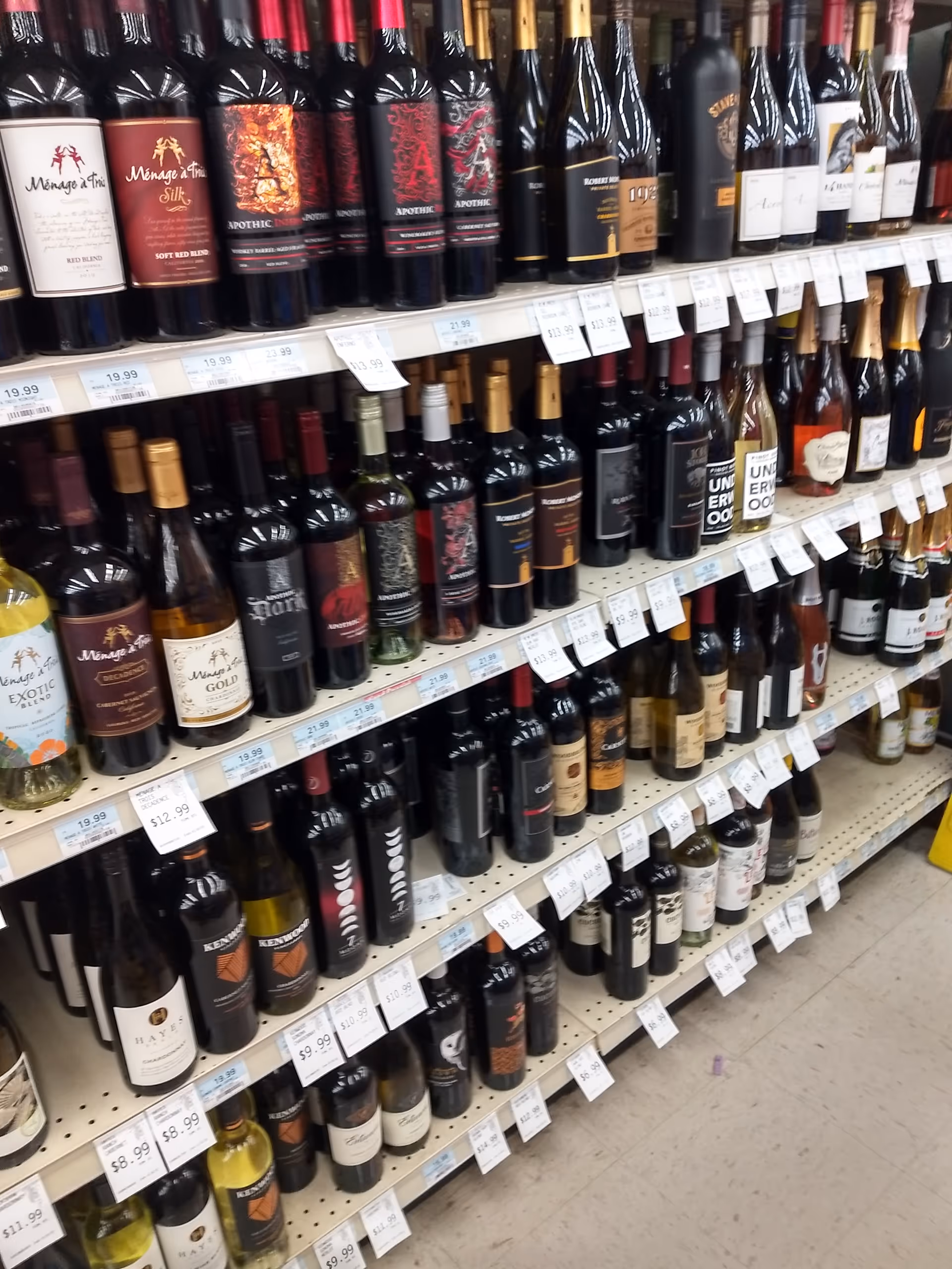 Rows of wine bottles line store shelves inside Discount Drug Mart.