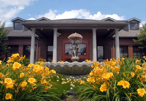 Front view of Hospice of Hope building with a fountain and yellow flowers.