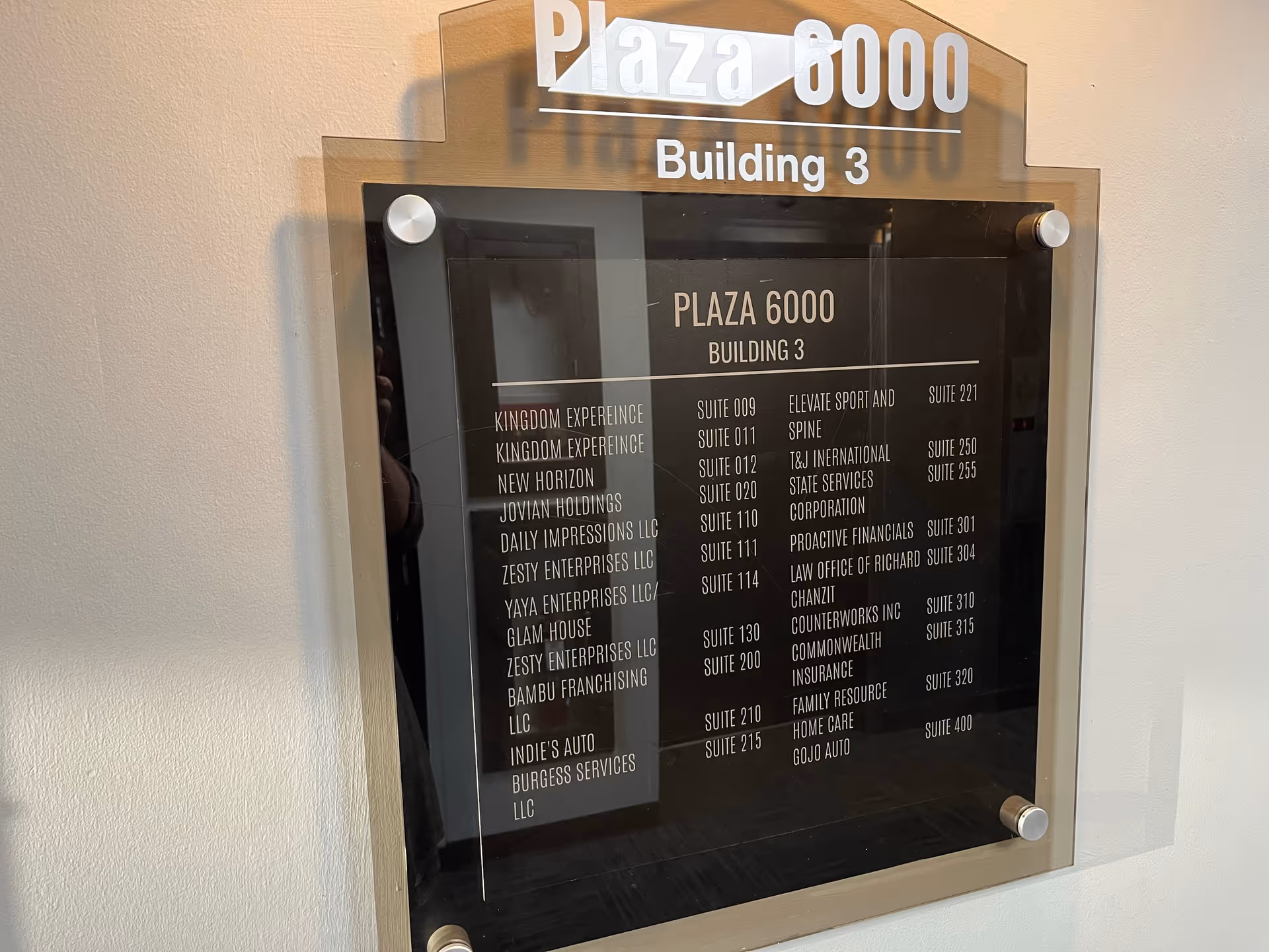An indoor plaque directory showing Plaza 6000 Building 3 with suite listings.