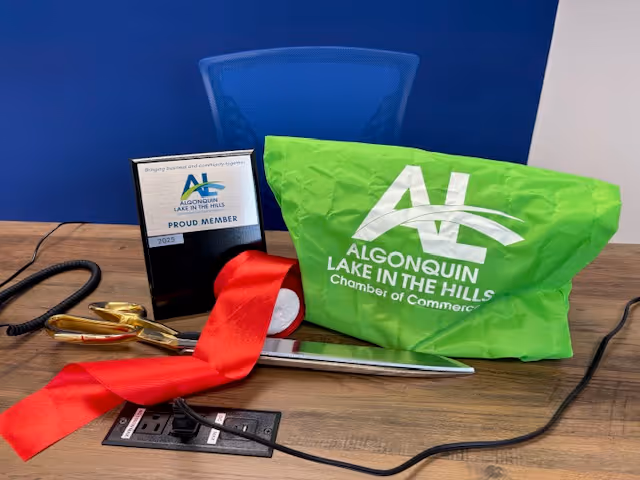 Desk scene with a green Algonquin Lake in the Hills Chamber bag, ribbon, plaque, and scissors.