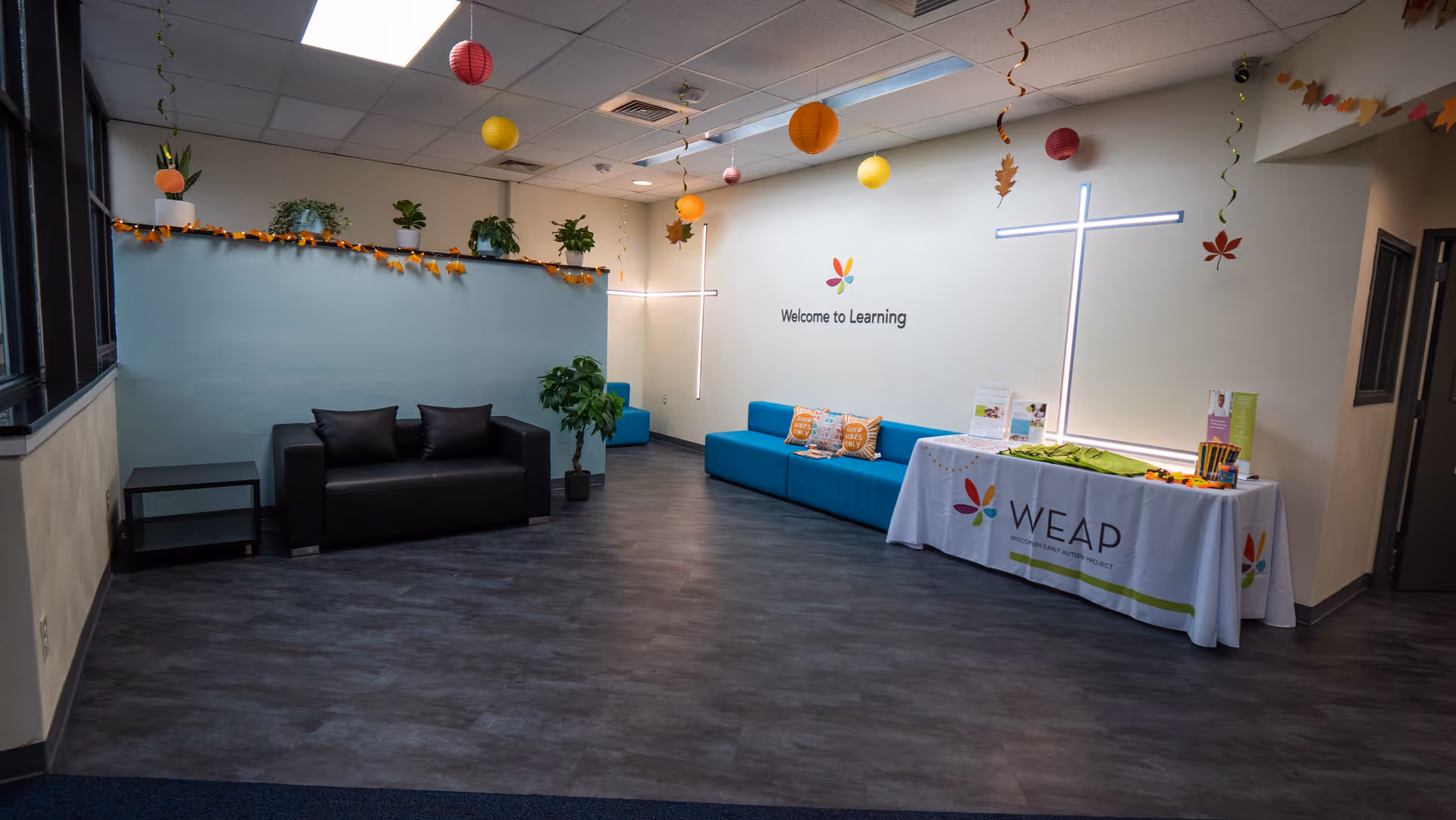 Spacious interior lounge with blue sectional seating, a WEAP table, and decorative hanging ornaments.