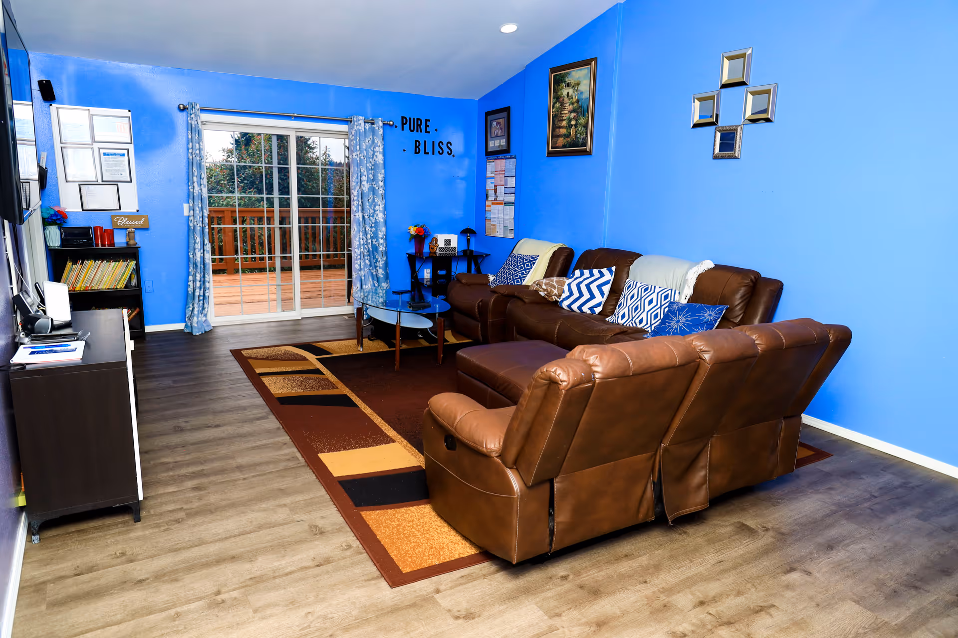 Bright blue living room with brown leather sectional and sliding glass door.