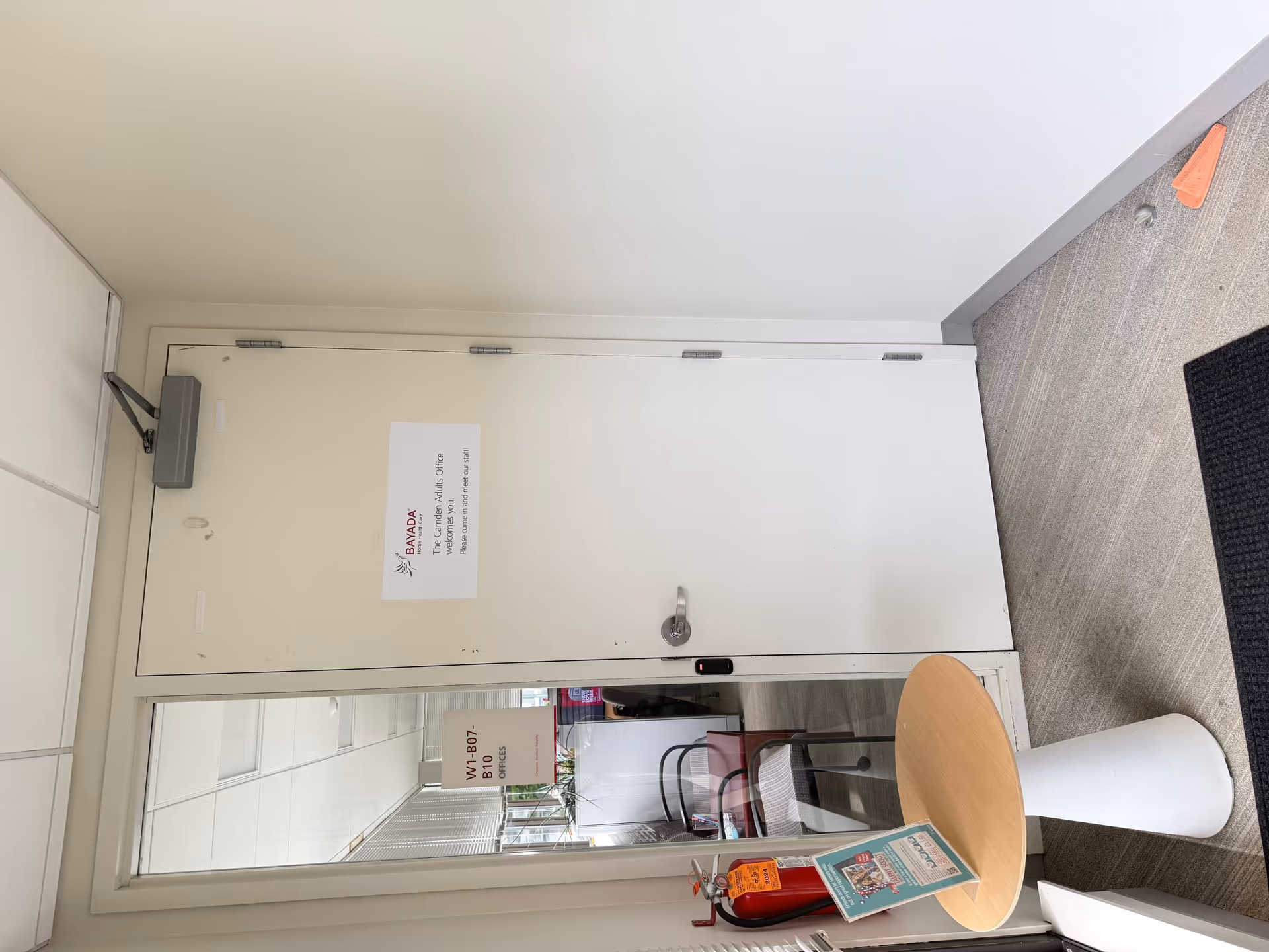 Interior hallway with a locked door, glass window, round table, and a fire extinguisher.