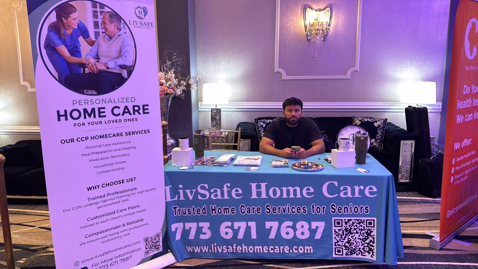 A LivSafe Home Care booth with banners and a man seated at a blue table indoors.