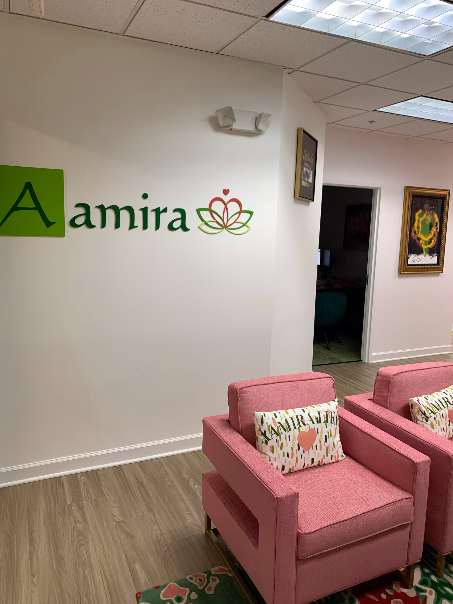 Interior lobby with pink chairs and a wall sign reading Aamira.