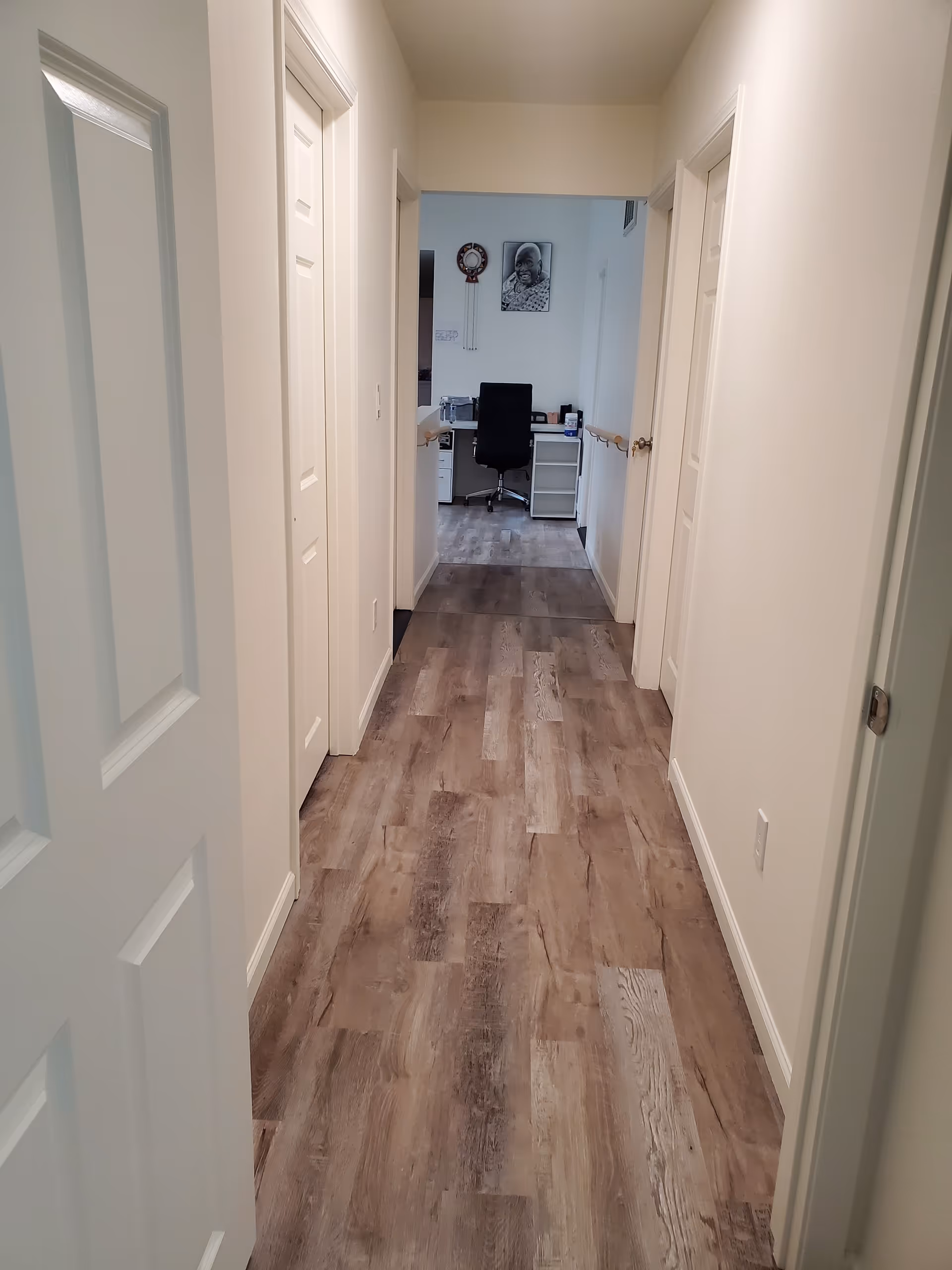 Long hallway inside a senior living facility leading to a small office desk.